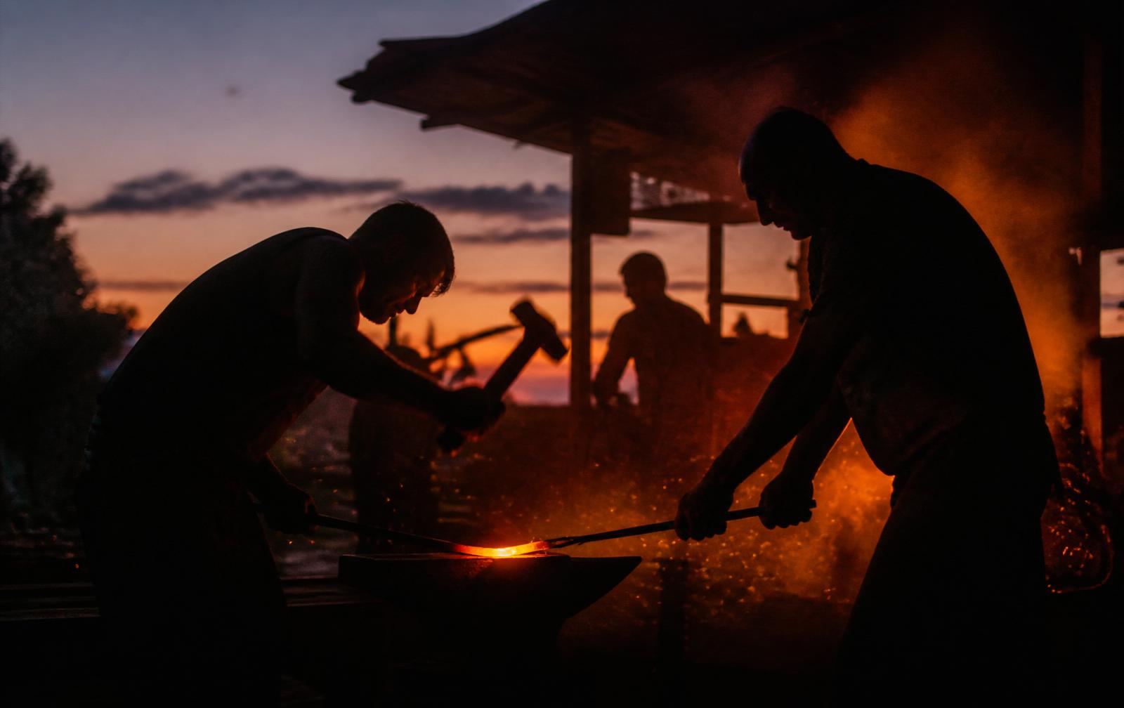 Men forging steel at dusk